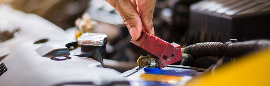 auto technician checking battery life with battery tester