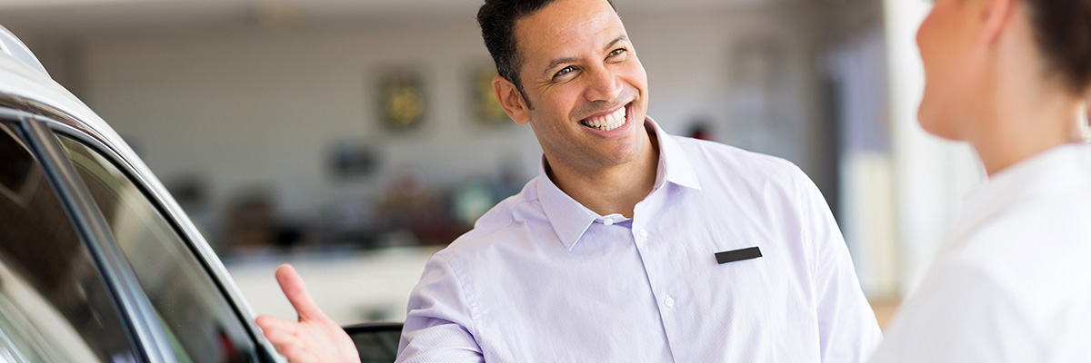 Spanish speaking dealership employee showing a customer a car