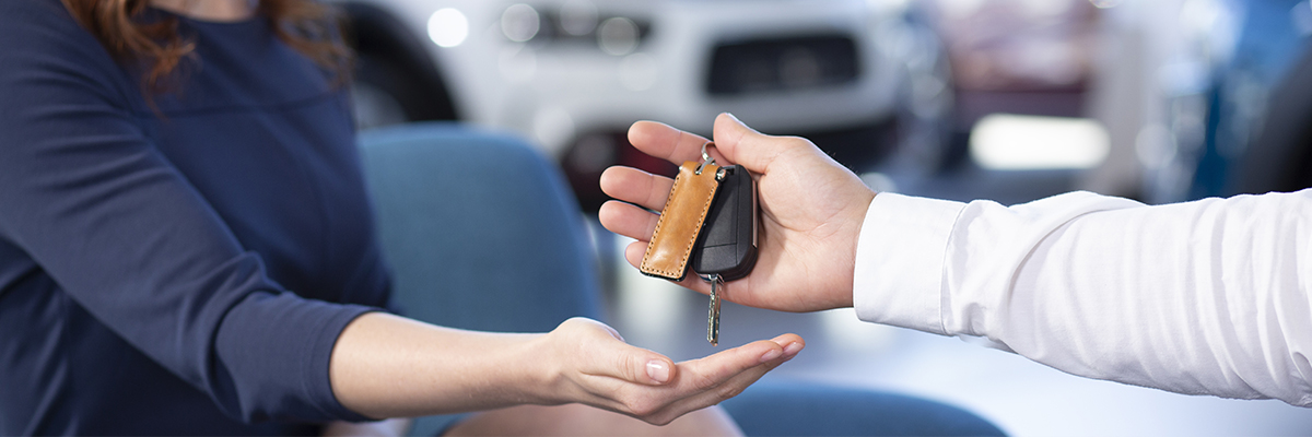 Dealership employee hadning new car keys to a customer