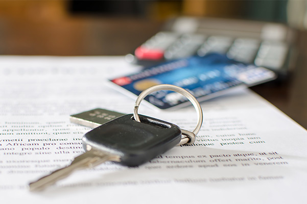 Car keys in focus with credit card and paperwork in background
