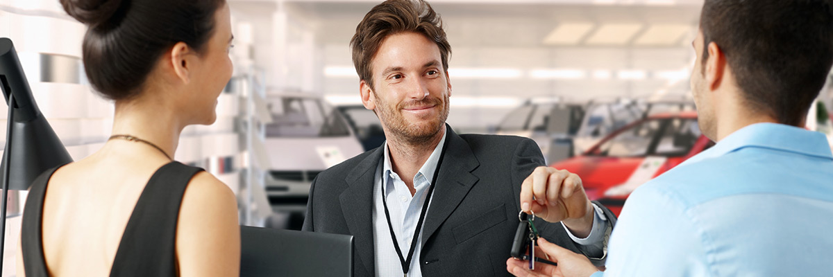Salesman handing customer car keys while smiling