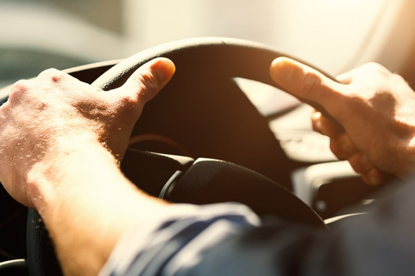 person with hands on wheel of car